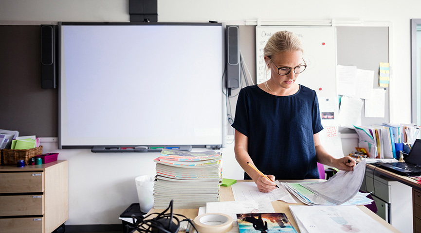 Kvinna som står och tittar på papper på ett skrivbord