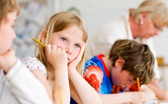 En elev som funderar på lektionen medan klasskamraterna blir hjälpa av läraren