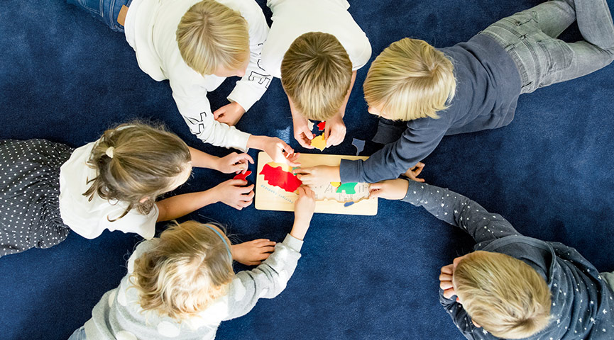 Lågstadieelever leker på golvet med pussel