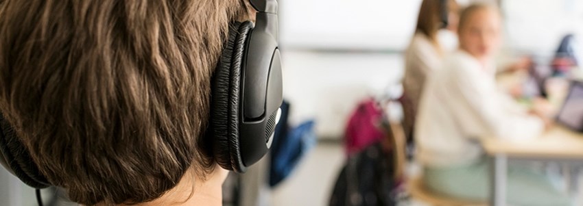En elev sitter med hörlurar under en lektion