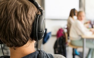 En elev sitter med hörlurar under en lektion
