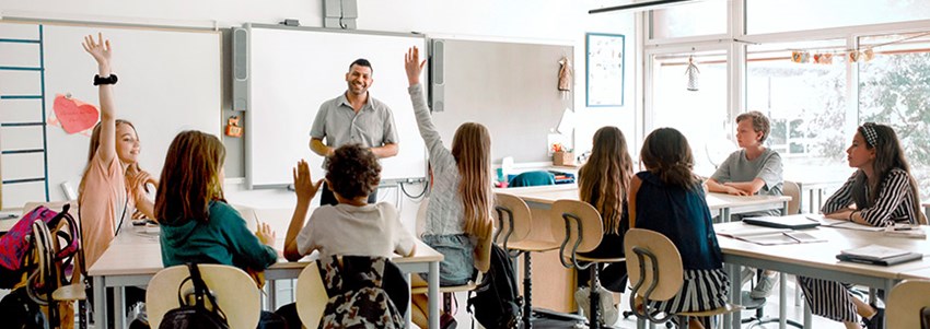 En lärare står och undervisar en mellanstadieklass i ett klassrum