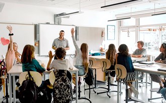 En lärare står och undervisar en mellanstadieklass i ett klassrum