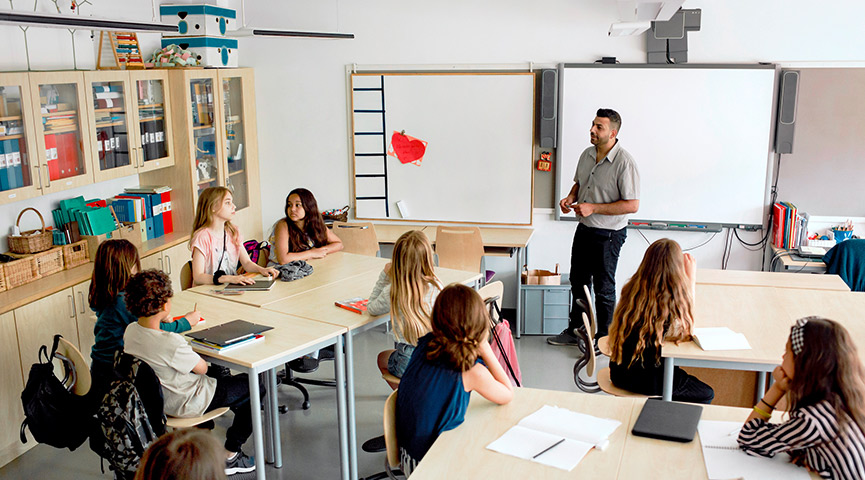 En lärare står och undervisar en mellanstadieklass i ett klassrum