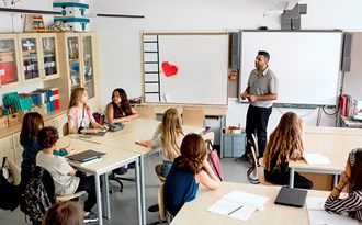 En lärare står och undervisar en mellanstadieklass i ett klassrum