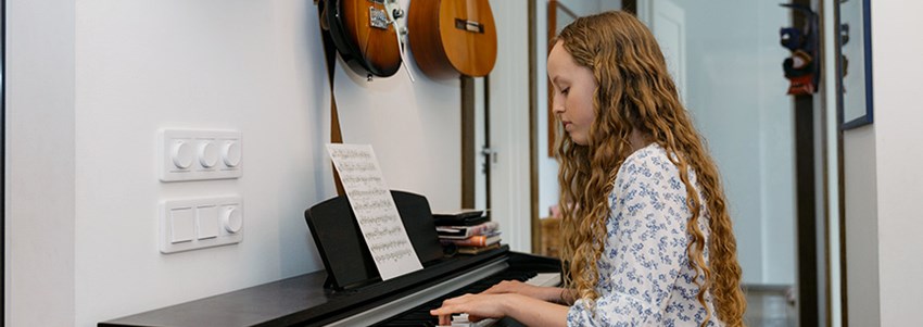 En högstadieelev sitter vid ett piano