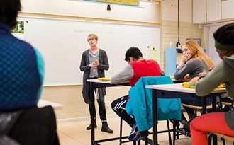 En lärare står vid whiteboardtavlan och undervisar en högstadieklass