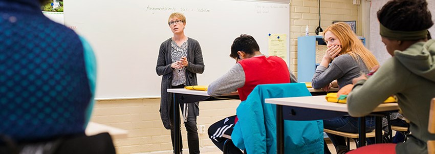 En lärare står vid whiteboardtavlan och undervisar en högstadieklass