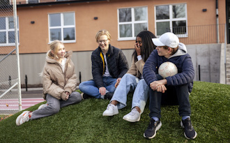 Elever sitter utanför en skola