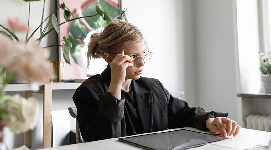 En högstadieelev studerar på en iPad hemifrån vid ett fönster