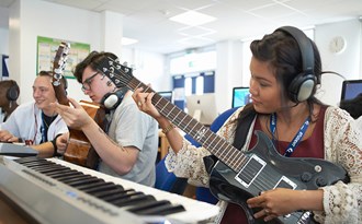En musiklektion i gymnasiet där eleverna spelar gitarr och keyboard