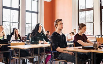 En gymnasieklass sitter och lyssnar i ett klassrum