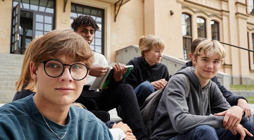 En grupp gymnasieelever sitter på en trappa