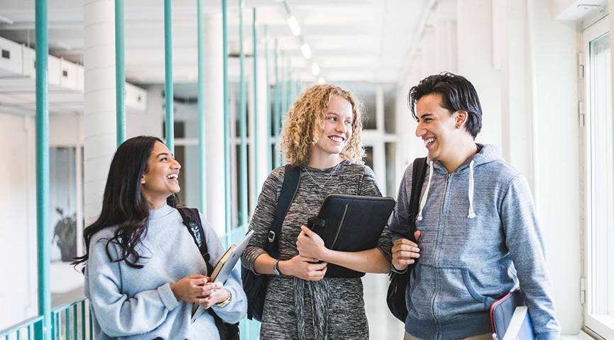 Tre vuxenstudenter går i en korridor
