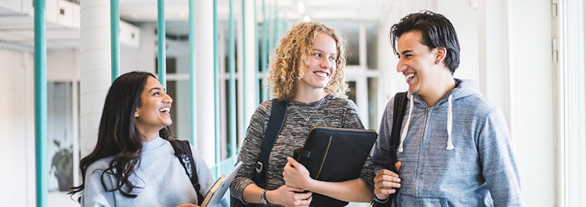 © Tre vuxenstudenter går i en korridor