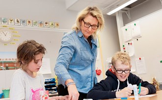 Två elever som klipper och klistrar får hjälp från lärare