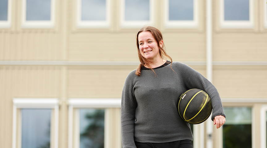 En idrottslärare står på skolgården med en basketboll