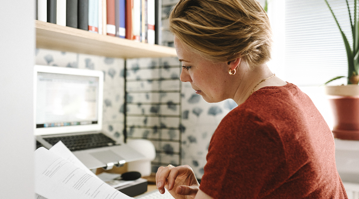 en vuxen kvinna läser en rapport framför datorn
