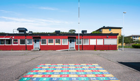 Skolbyggnad och skolgård under klarblå himmel