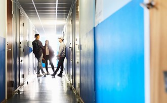 Tre högstadieelever står långt bort i en korridor